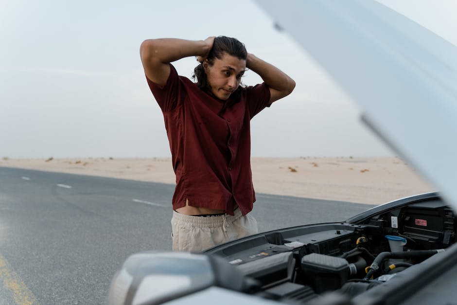 Image depicting a frustrated person with their broken down car on the side of the road