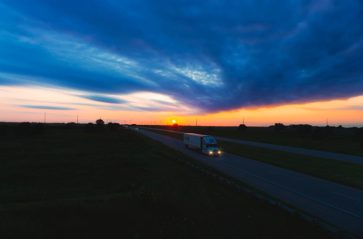 Image of a business delivery truck on a road with a sunset backdrop, representing the topic of preventing delivery delays.