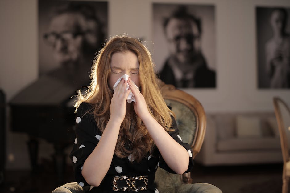 Image of a person holding a tissue while sneezing indicating illness.