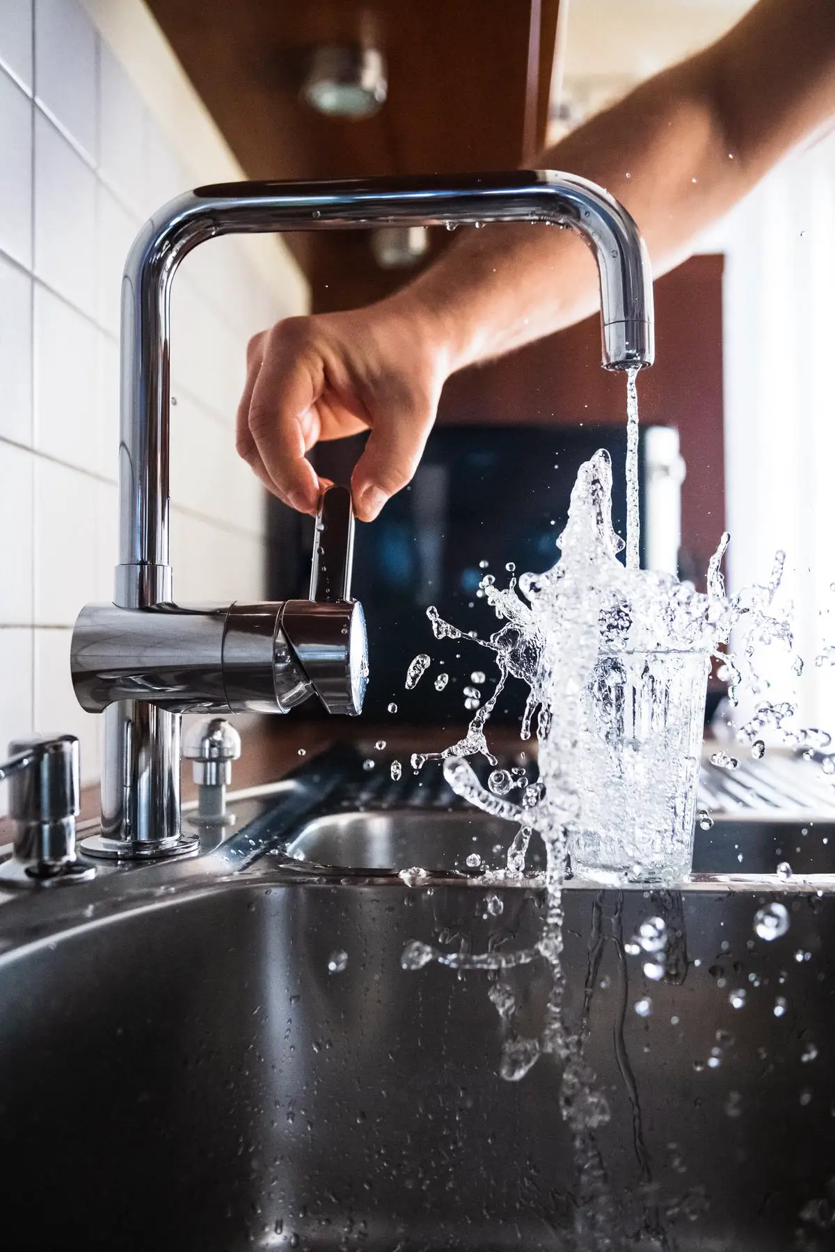 Image of a person holding a wrench and fixing a leaky faucet.