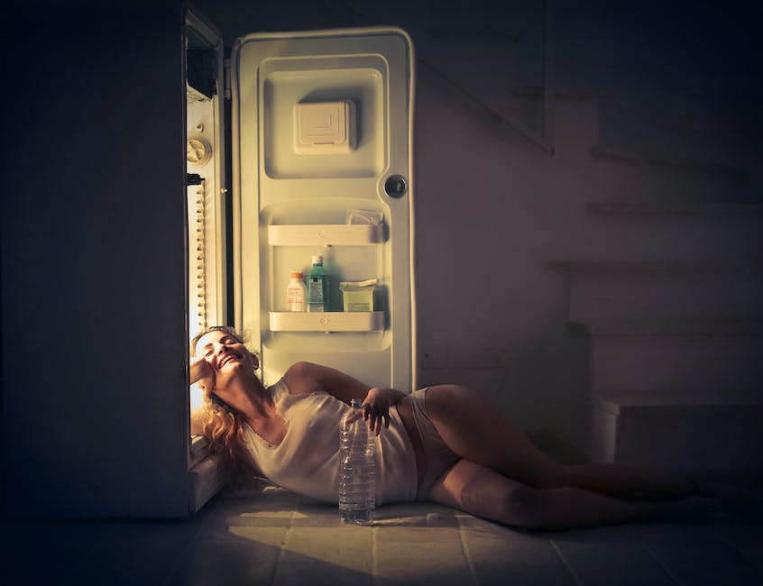 A person approaching the refrigerator with a spotlight on the food inside, signaling the temptation of late night snacks.