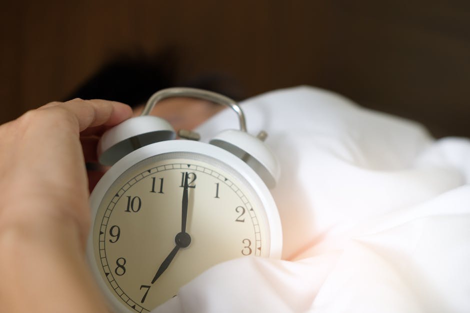 An image of a person sleeping on a bed with a clock in the foreground indicating that they have overslept.