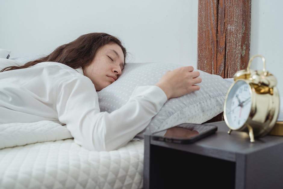 A person sleeping peacefully in bed with an alarm clock in the foreground, indicating the importance of managing oversleeping.