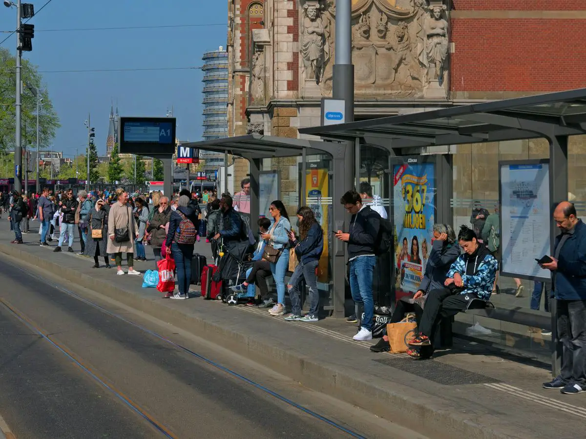 Illustration of city streets with a crowded bus and people waiting at a bus stop.