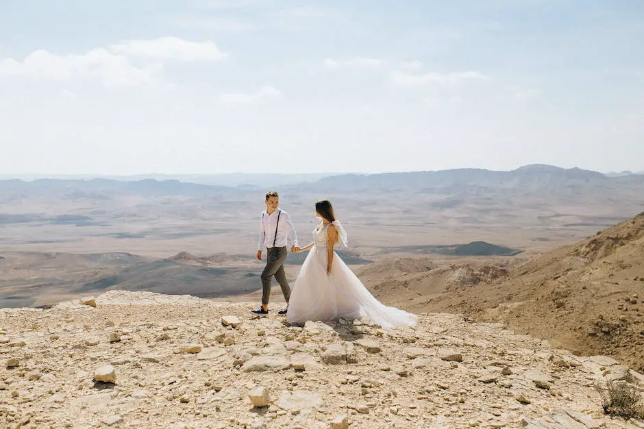 A couple holding hands while standing in front of a beautiful mountainous landscape. The image conveys the idea of a destination wedding, with an emphasis on the travel involved.